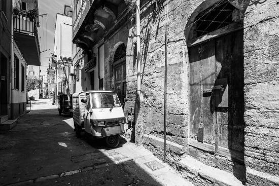 Black and White Image of Sciacca Old Town with a Piaggio Ape Three-Wheeled Vehicle near Old Buildin