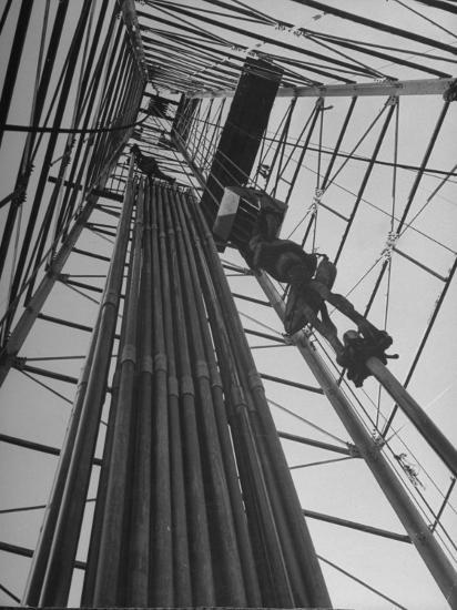 Vertical View of Oil Rig Showing Stacked Drill Pipes and Derrick Man at Work